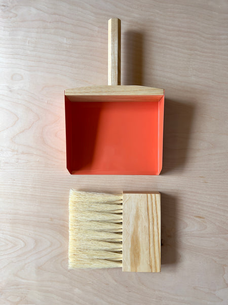 Dark wood hand broom and dustpan with orange metal sides and blonde horse hair bristles.